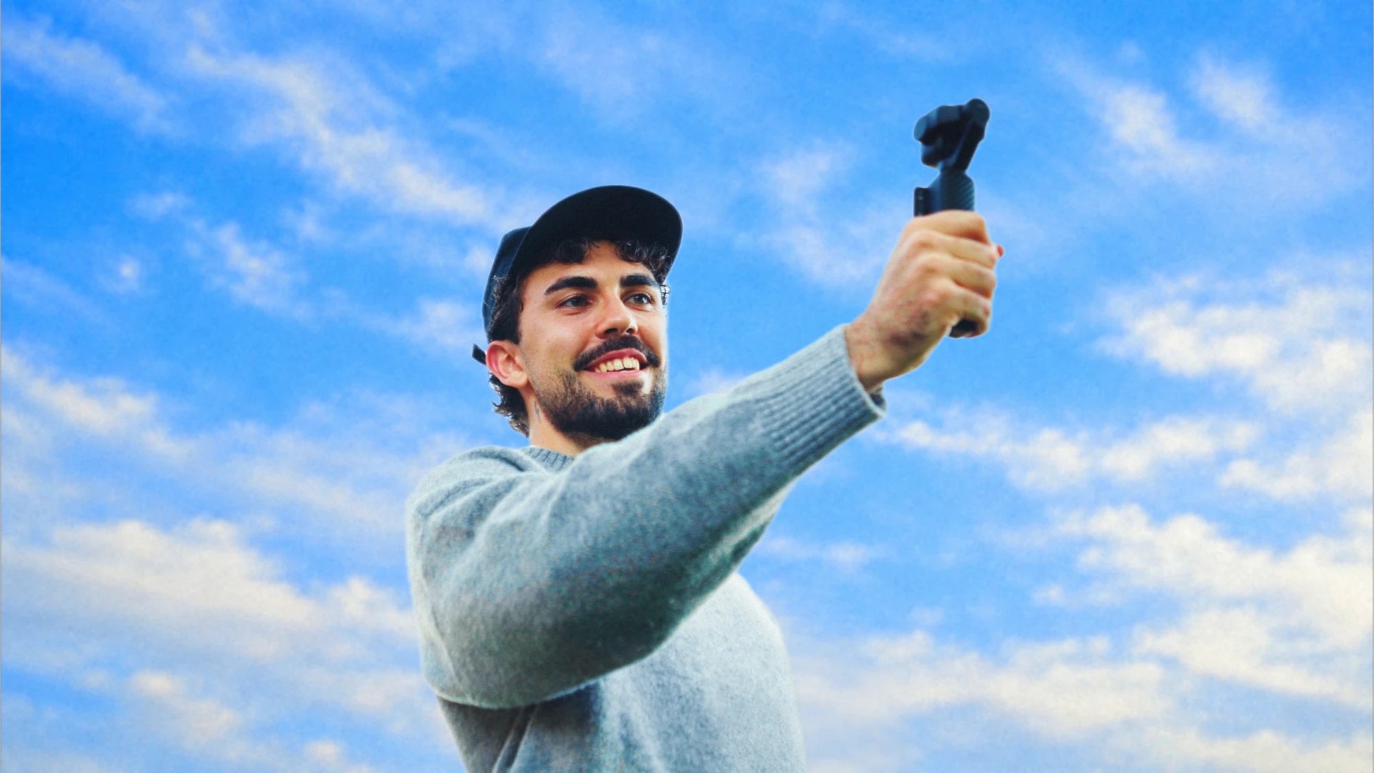 Ángel Luis grabando con una cámara de mano frente a un cielo azul